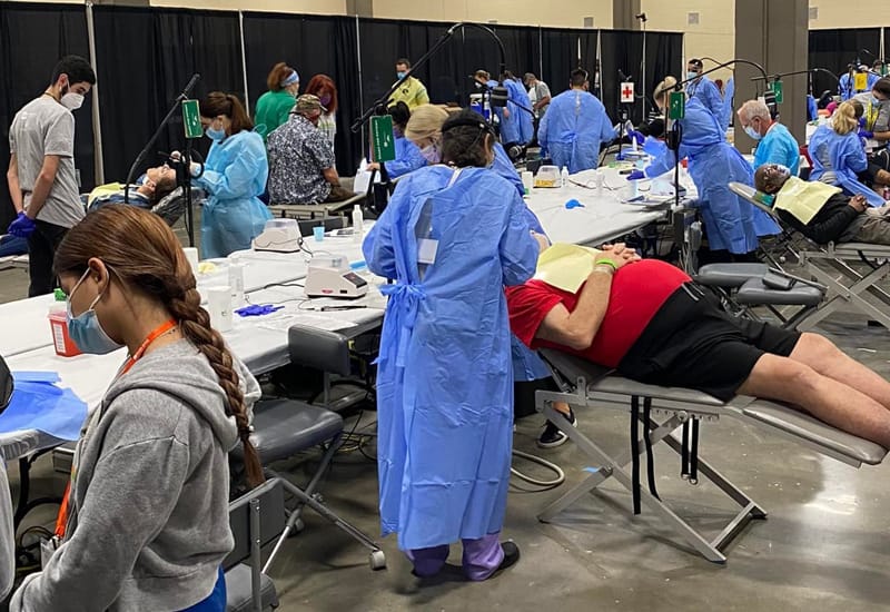 Dentists at a charity event where they help fix teeth for economically disadvantaged persons - With patient who looks happy.